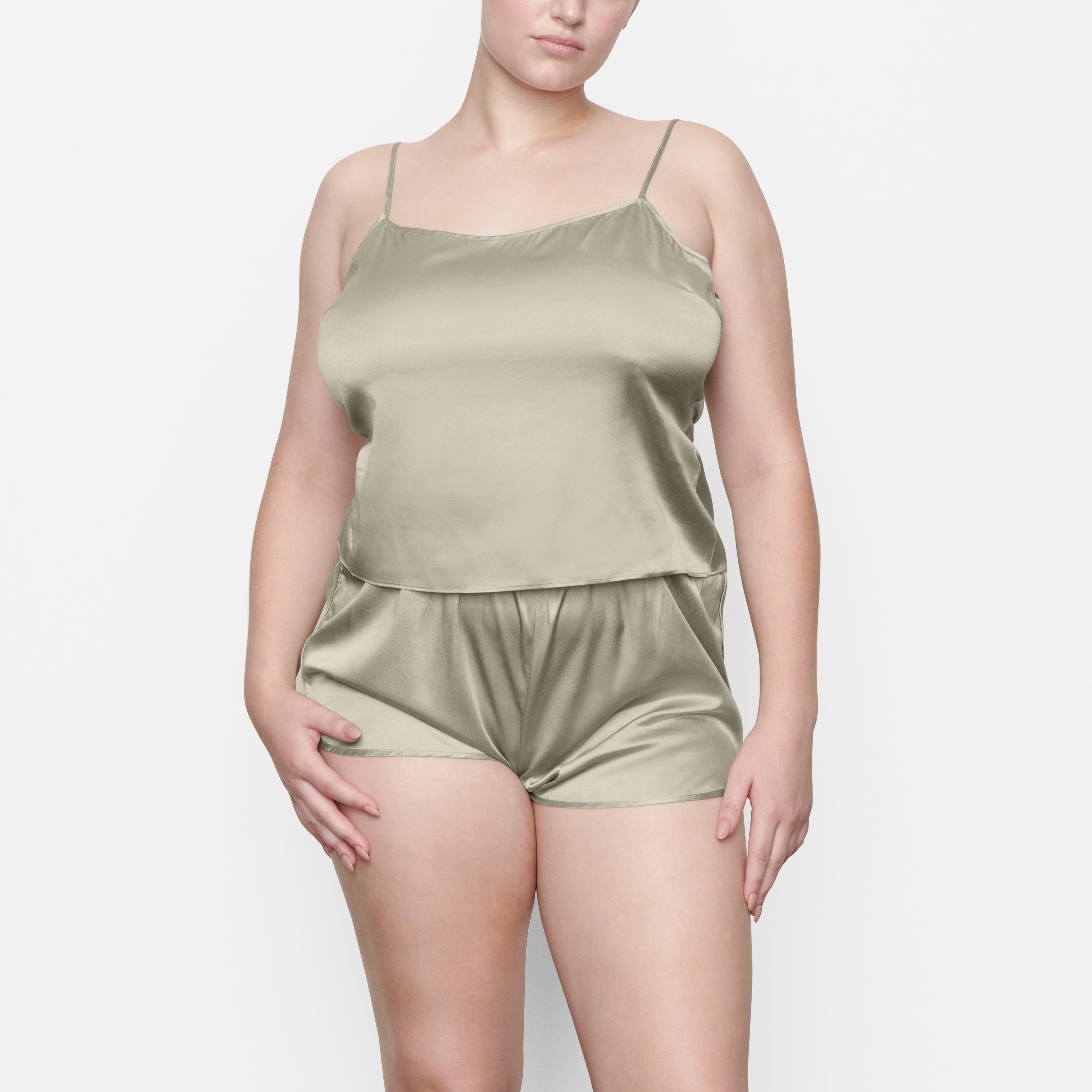 A MODEL STANDS FACING FORWARD WEARING THE SKIMS SILK SLEEP TANK IN TALC | SEE: M, L, XL