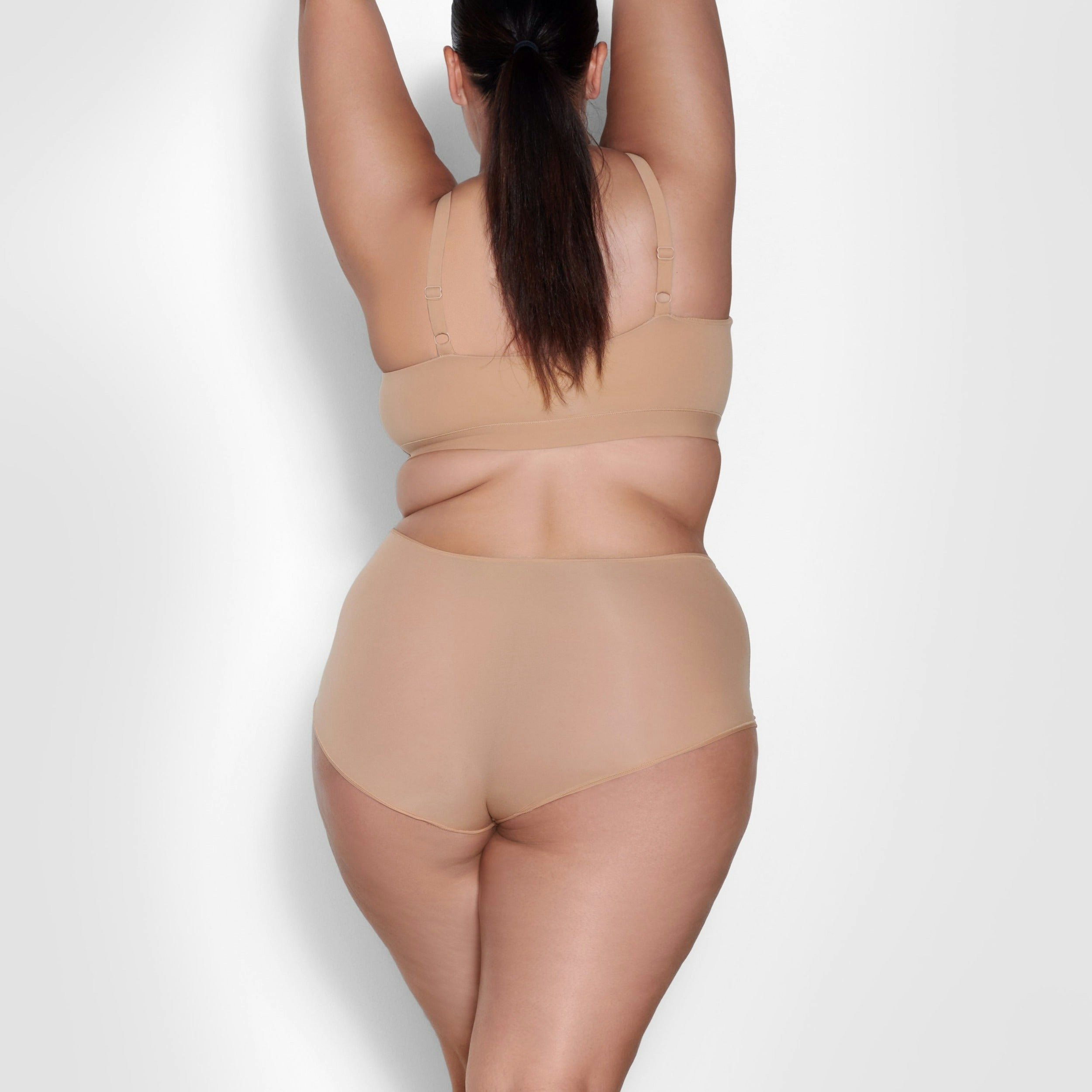 A MODEL STANDS WITH HER BACK TO THE CAMERA SHOWING THE FITS EVERYBODY BOY SHORT | OCHRE