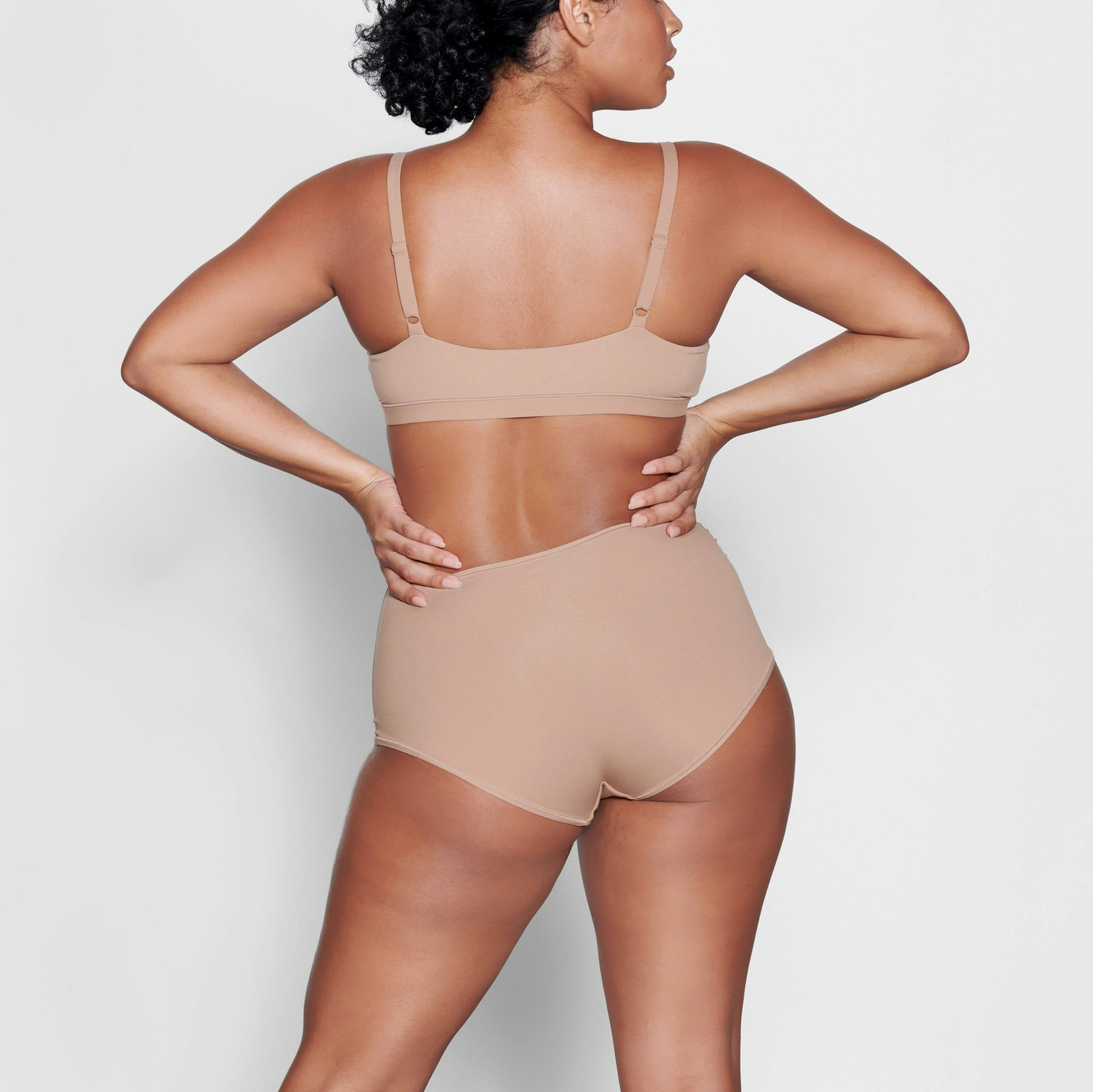 A MODEL STANDS WITH HER BACK TO THE CAMERA SHOWING THE FITS EVERYBODY BOY SHORT | SIENNA