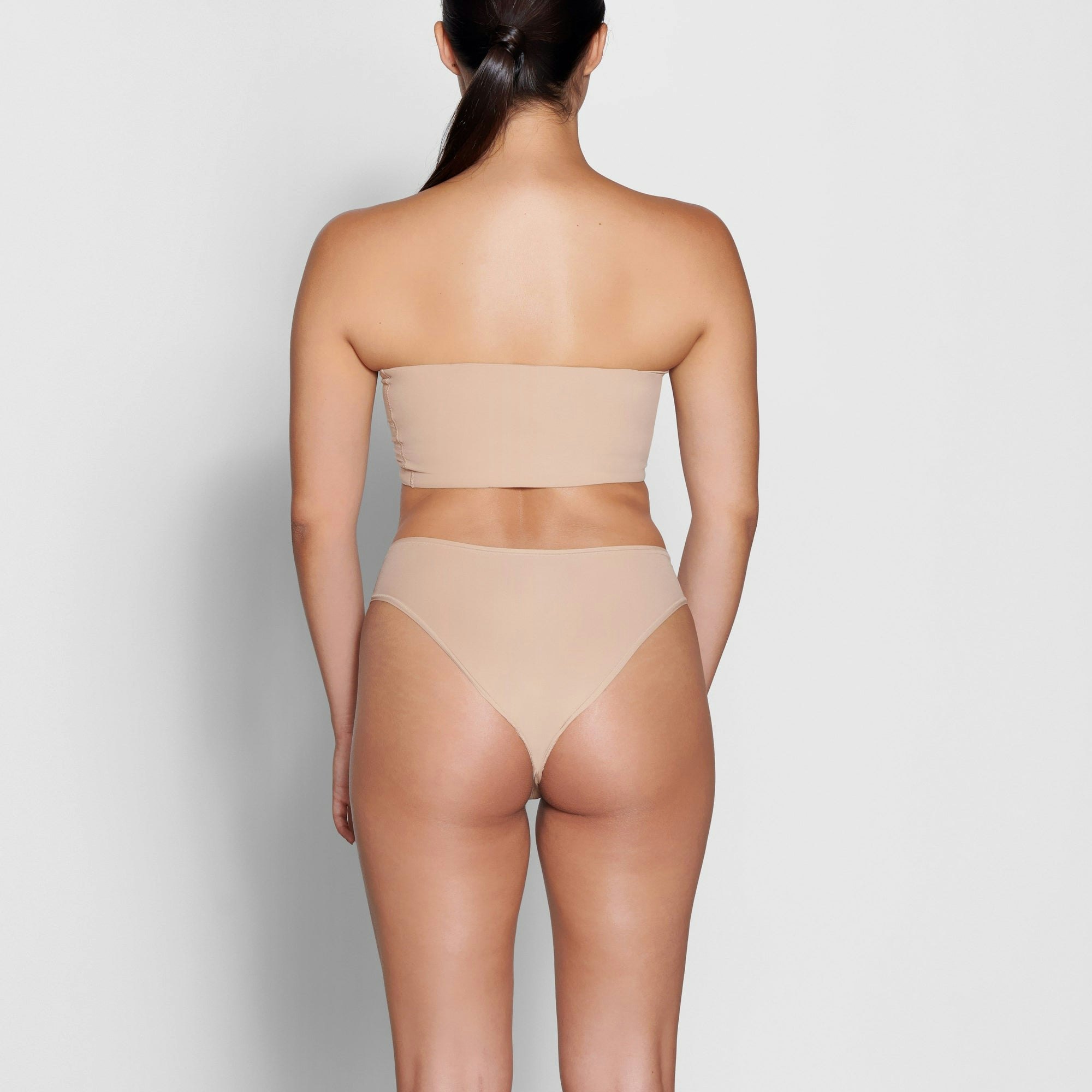 A MODEL STANDS WITH HER BACK TO THE CAMERA SHOWING THE FITS EVERYBODY CHEEKY BRIEF | CLAY
