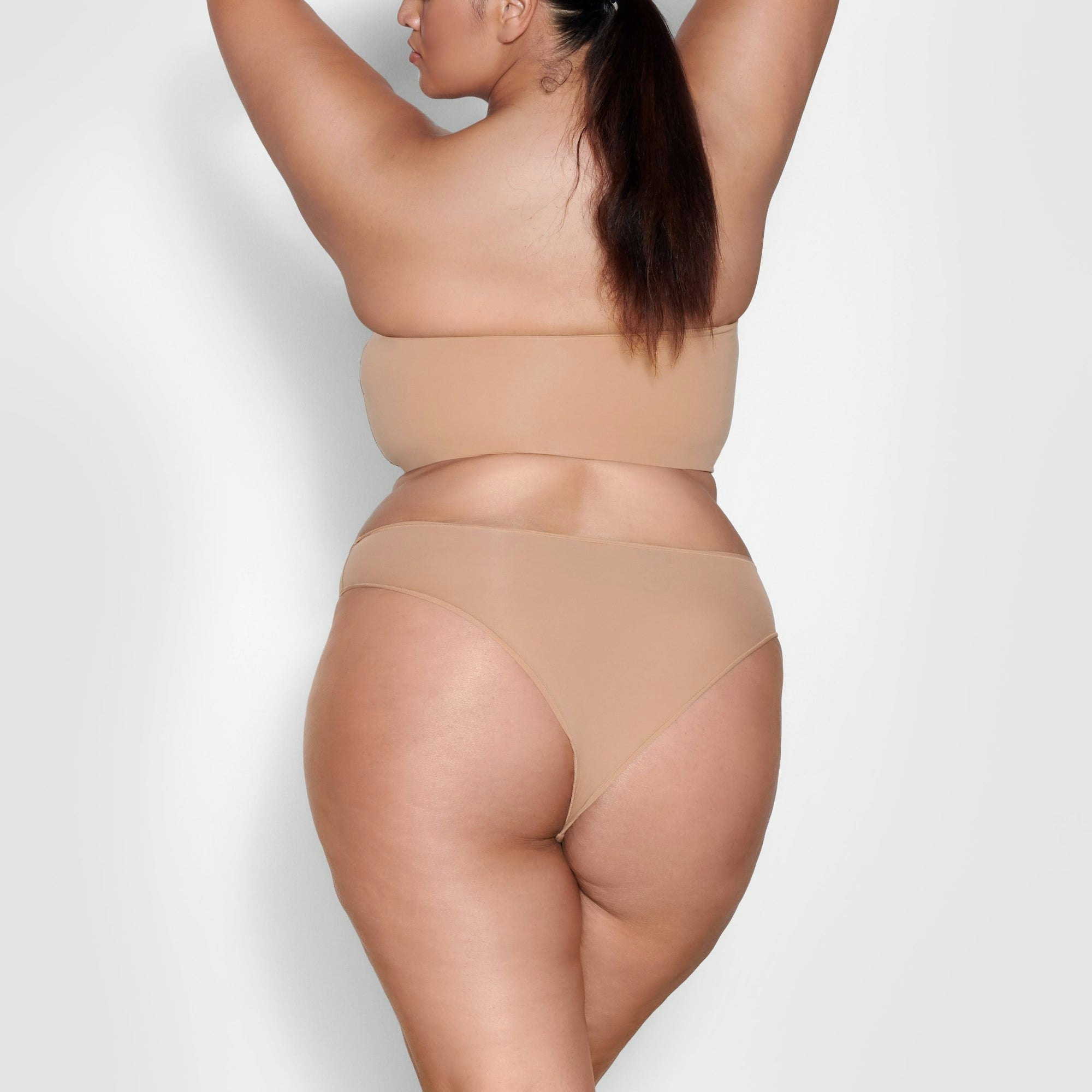 A MODEL STANDS WITH HER BACK TO THE CAMERA SHOWING THE FITS EVERYBODY CHEEKY BRIEF | OCHRE