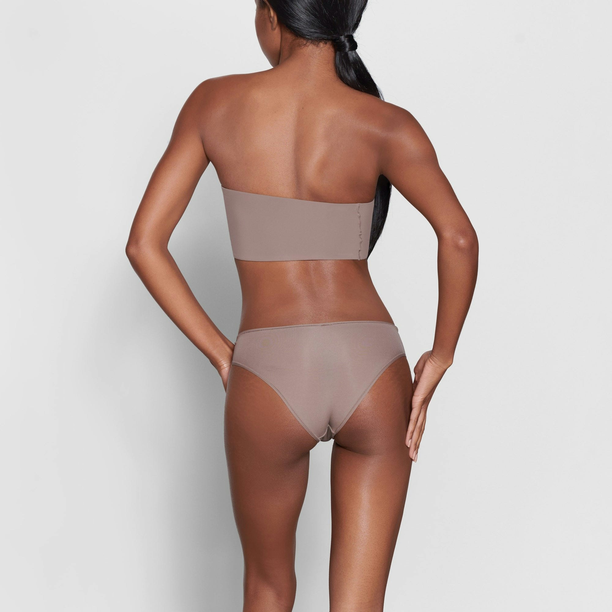 A MODEL STANDS WITH HER BACK TO THE CAMERA SHOWING THE FITS EVERYBODY CHEEKY BRIEF | UMBER