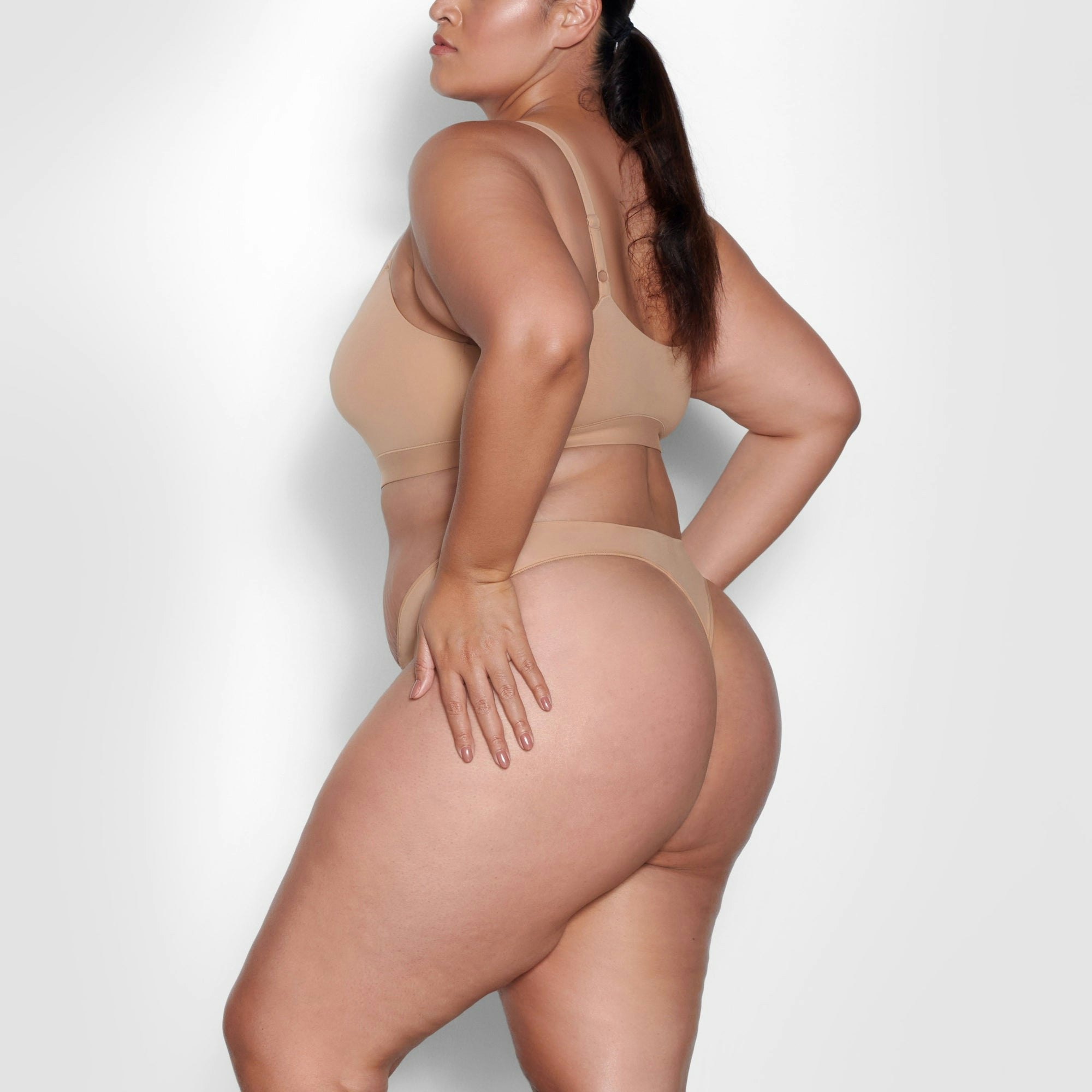 A MODEL STANDS SIDEWAYS SHOWING THE PROFILE OF THE FITS EVERYBODY THONG | OCHRE