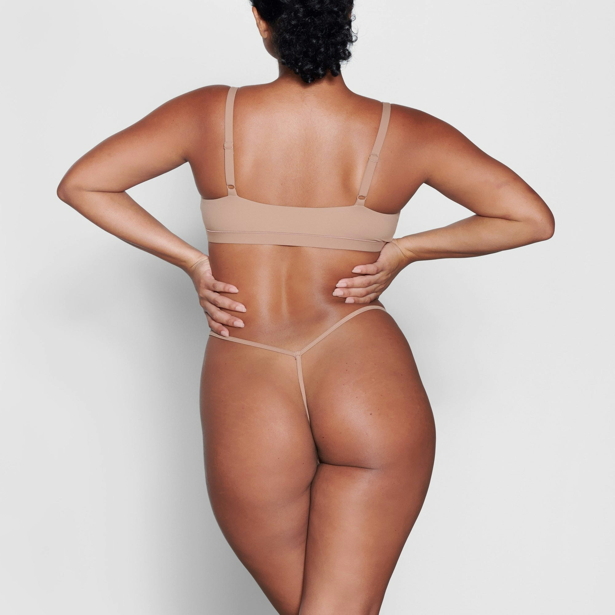 A MODEL STANDS WITH HER BACK TO THE CAMERA SHOWING THE FITS EVERYBODY T STRING THONG | SIENNA