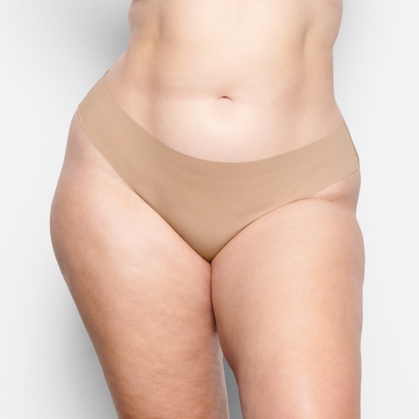 A MODEL STANDS FACING FORWARD WEARING THE SKIMS FREE CUT CHEEKY HIPSTER IN CLAY | SEE: 2X, 3X, 4X | FOCUS: 0.1, 0.9, 0.9