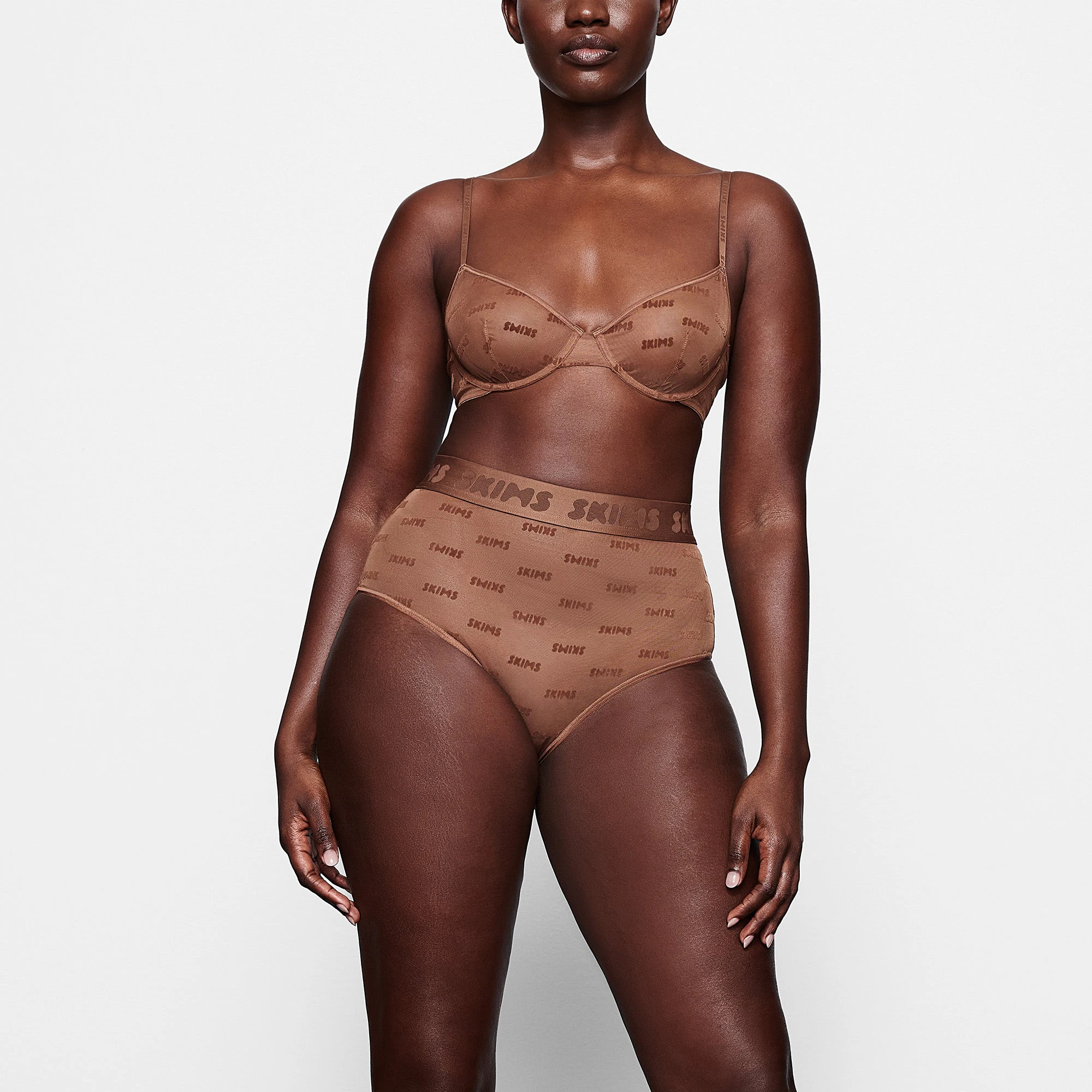 A MODEL STANDS FACING FORWARD WEARING THE SKIMS AFTER HOURS HIGH WAIST BRIEF IN JASPER | SEE: M, L, XL