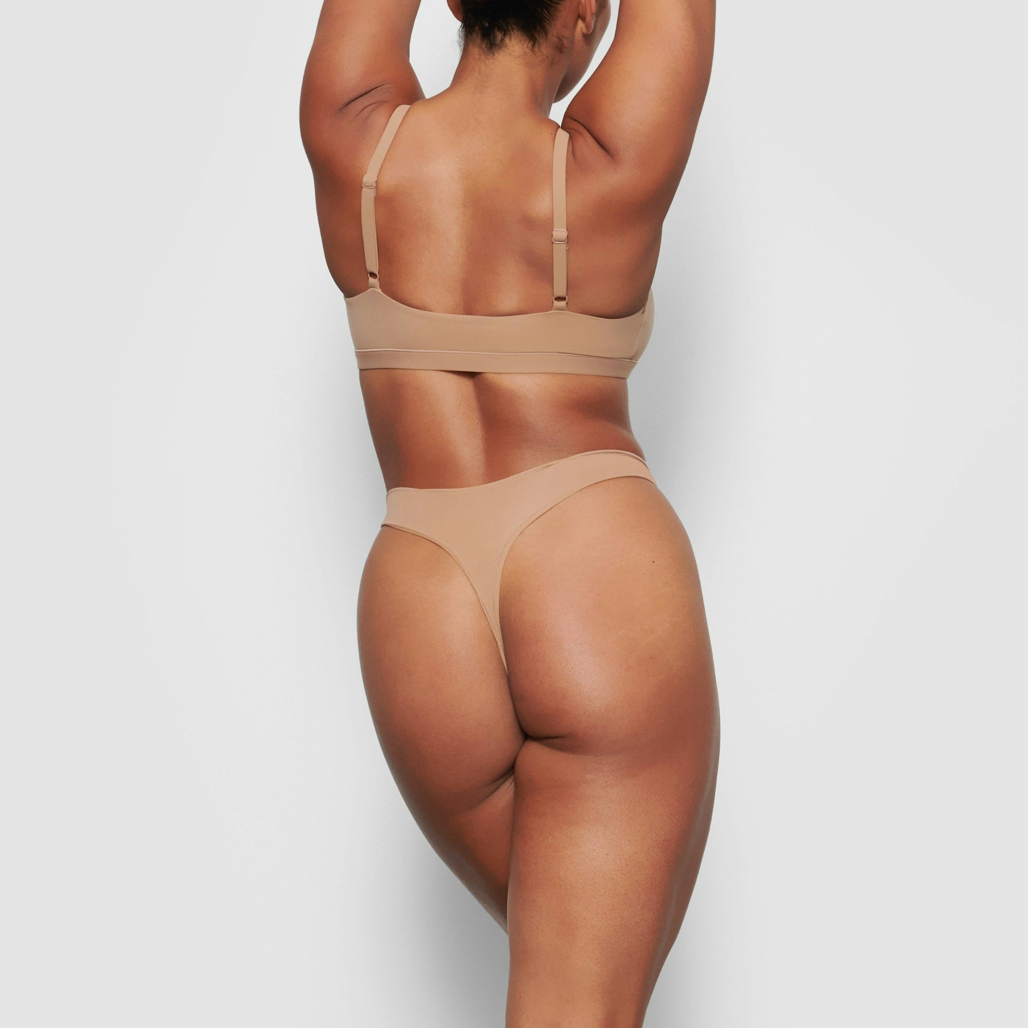 A MODEL STANDS WITH HER BACK TO THE CAMERA SHOWING THE FITS EVERYBODY THONG | SIENNA