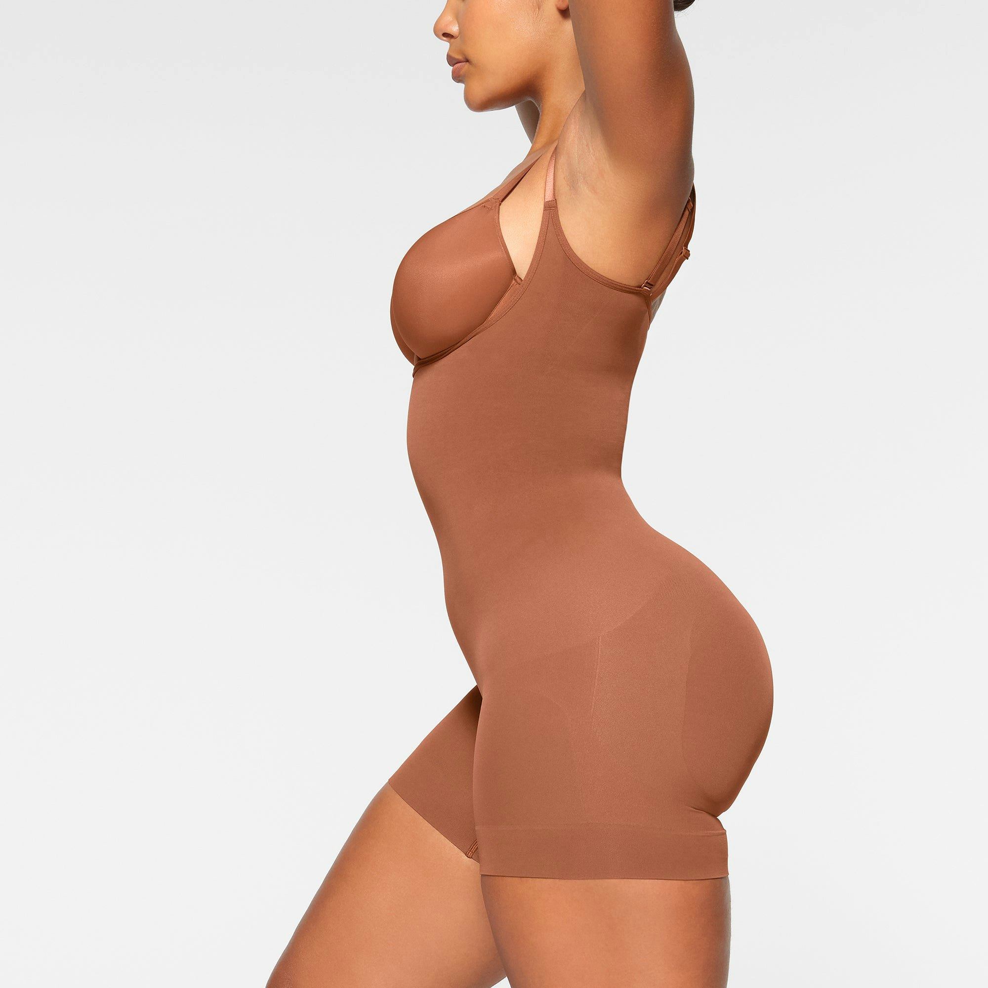 SEAMLESS SCULPT OPEN BUST SHORTIE BODYSUIT WORN BY A MODEL IN SIDE VIEW