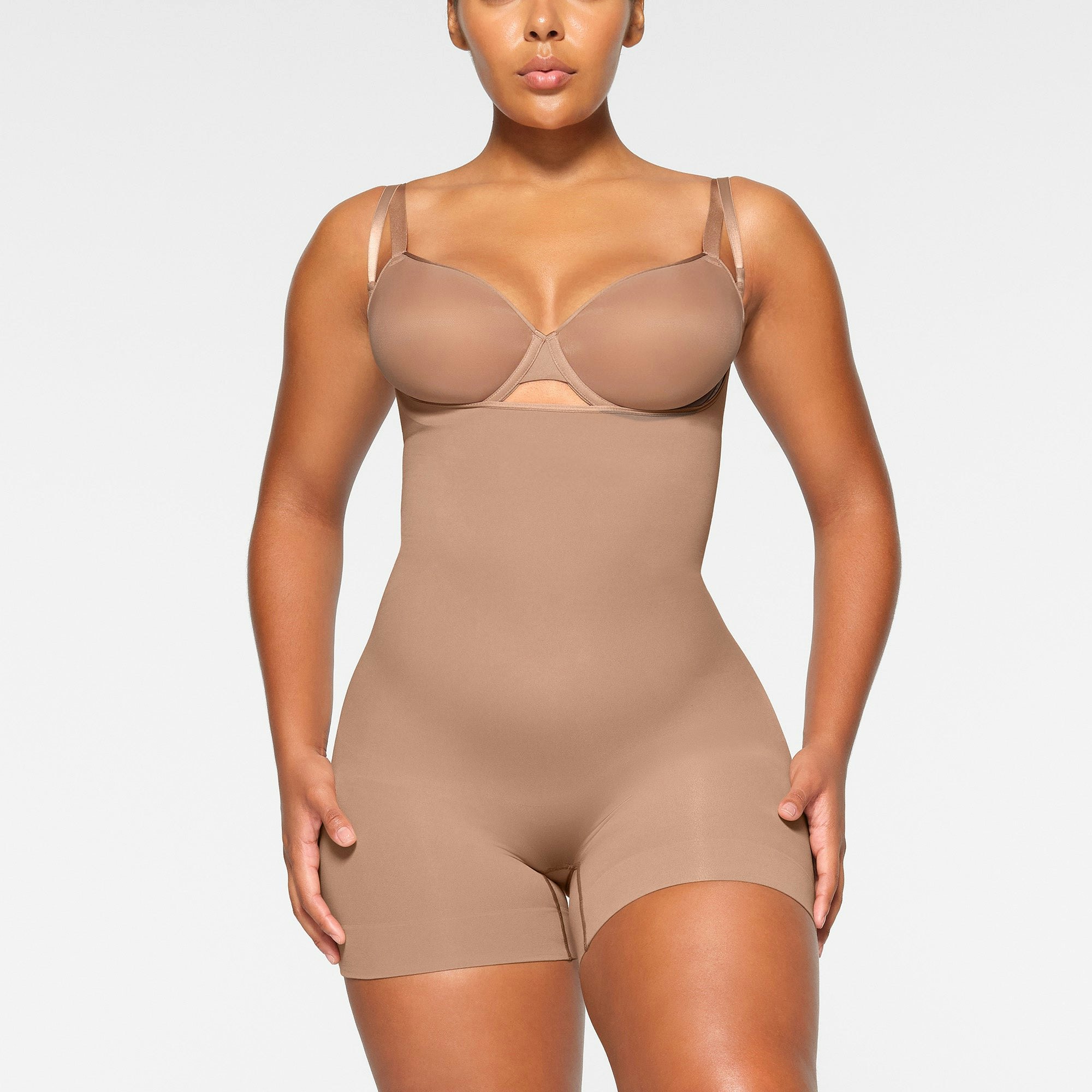 SEAMLESS SCULPT OPEN BUST SHORTIE BODYSUIT WORN BY A MODEL IN FRONT VIEW | SEE: M, L, XL