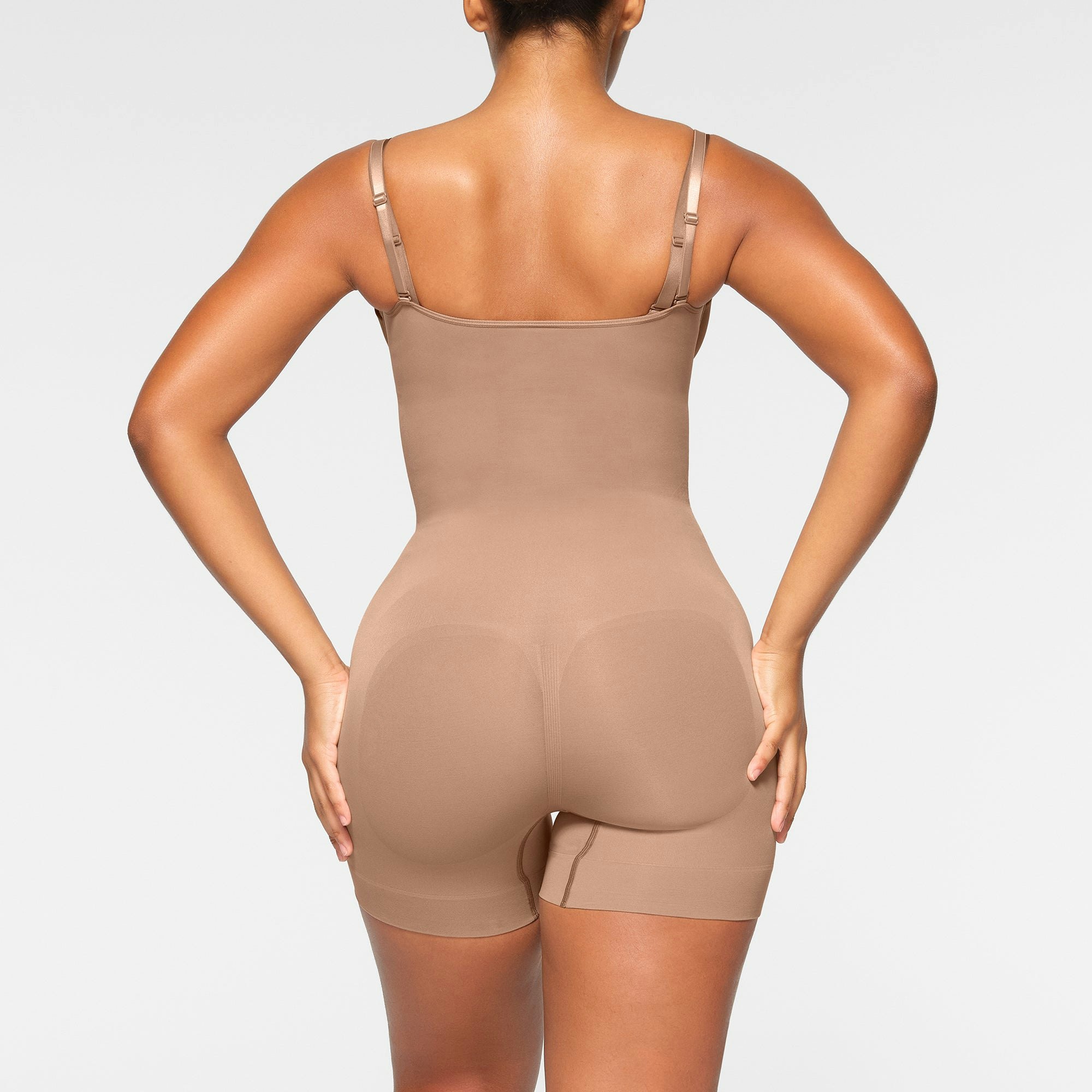 SEAMLESS SCULPT OPEN BUST SHORTIE BODYSUIT WORN BY A MODEL IN SIDE VIEW