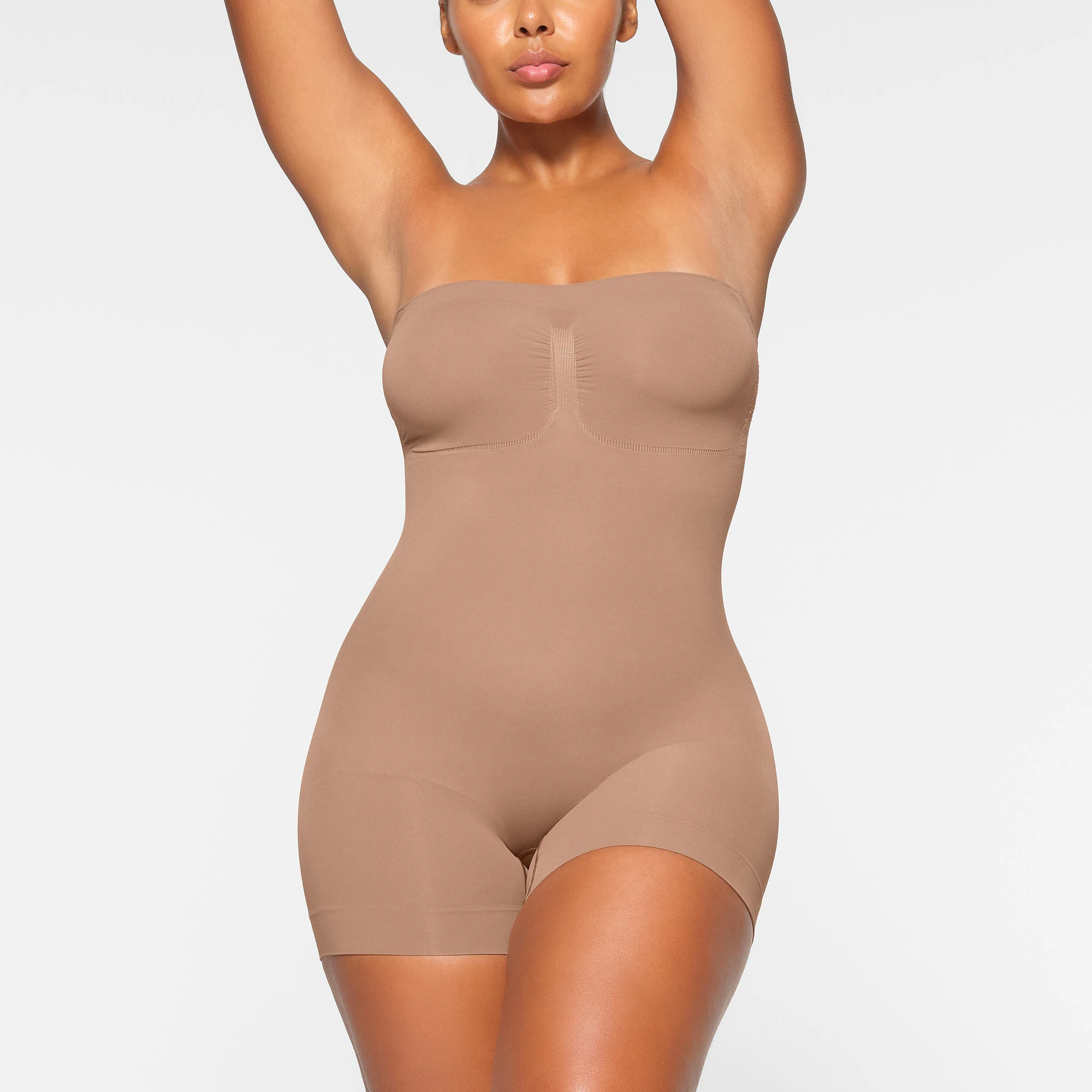 SEAMLESS SCULPT STRAPLESS MID THIGH BODYSUIT WORN BY A MODEL IN FRONT VIEW | SEE: M, L, XL