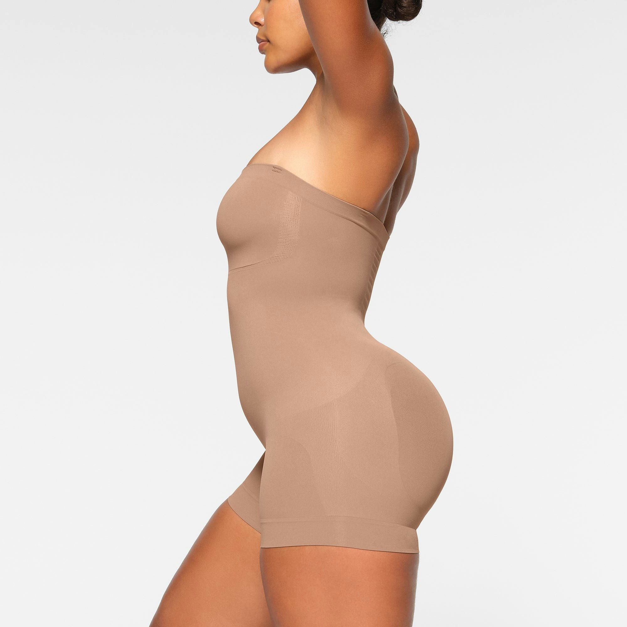 SEAMLESS SCULPT STRAPLESS MID THIGH BODYSUIT WORN BY A MODEL IN SIDE VIEW