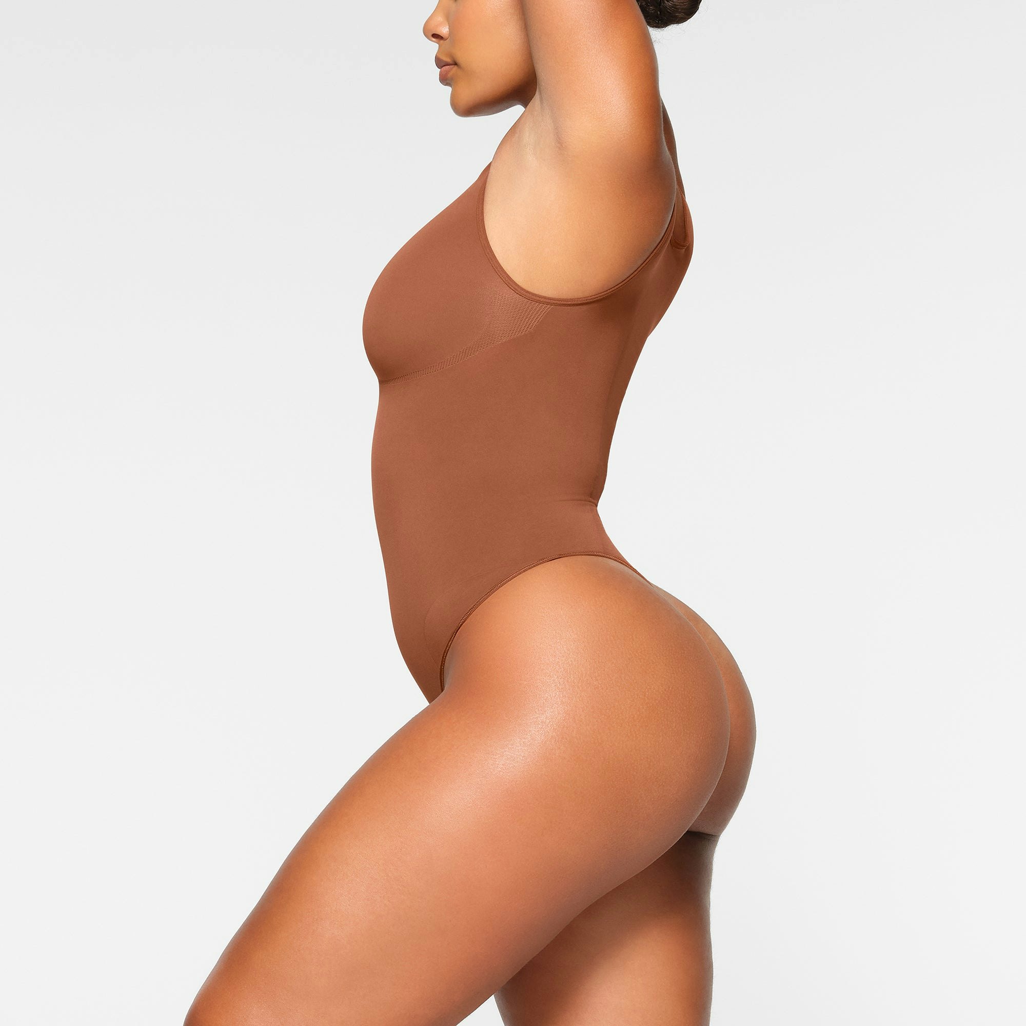 SEAMLESS SCULPT SCOOP NECK THONG BODYSUIT WORN BY A MODEL IN SIDE VIEW