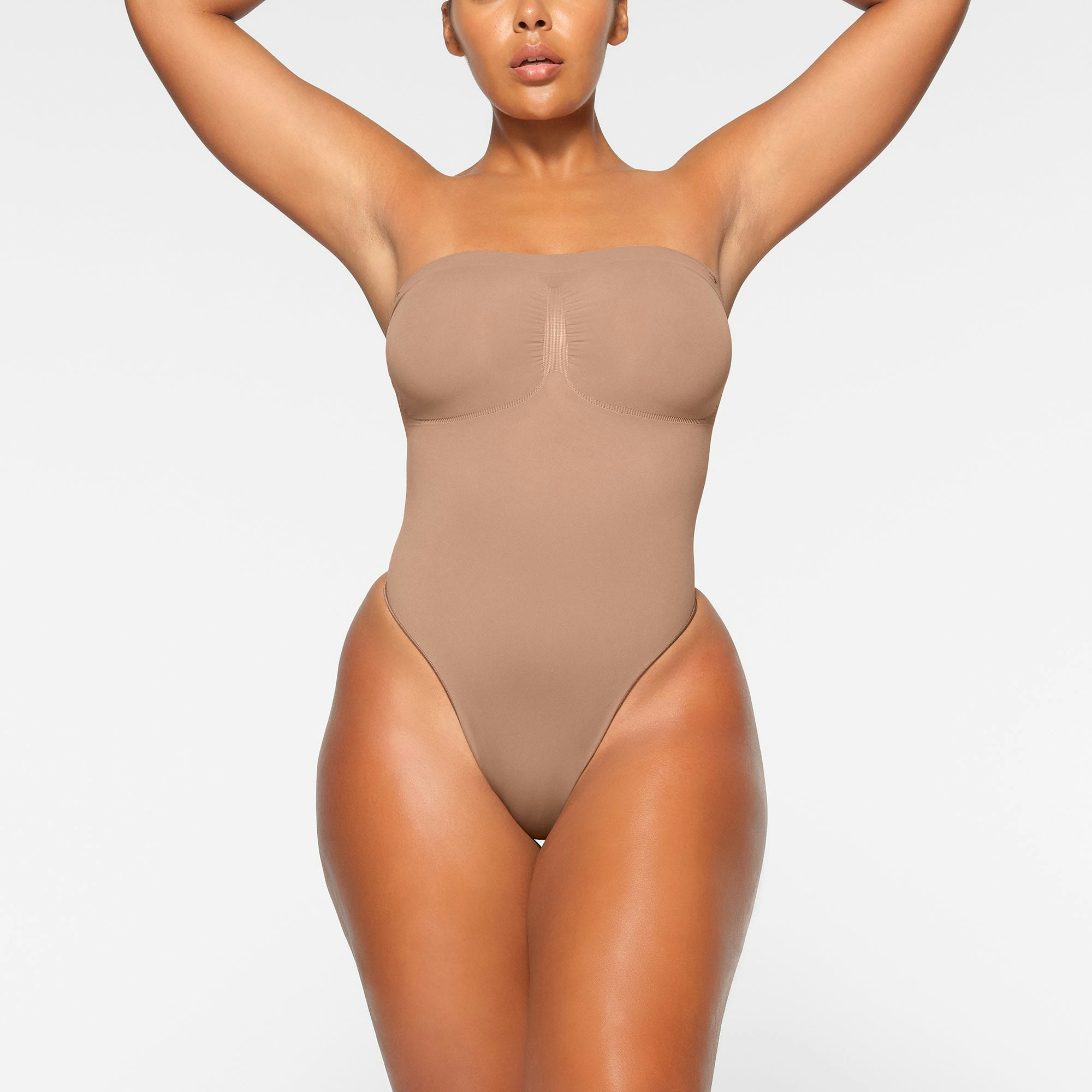 SEAMLESS SCULPT STRAPLESS THONG BODYSUIT WORN BY A MODEL IN FRONT VIEW | SEE: M, L, XL