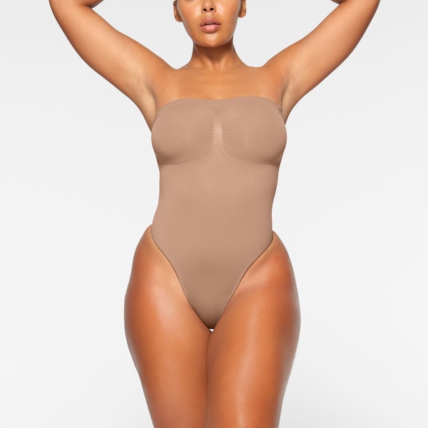 SEAMLESS SCULPT STRAPLESS THONG BODYSUIT WORN BY A MODEL IN FRONT VIEW | SEE: M, L, XL