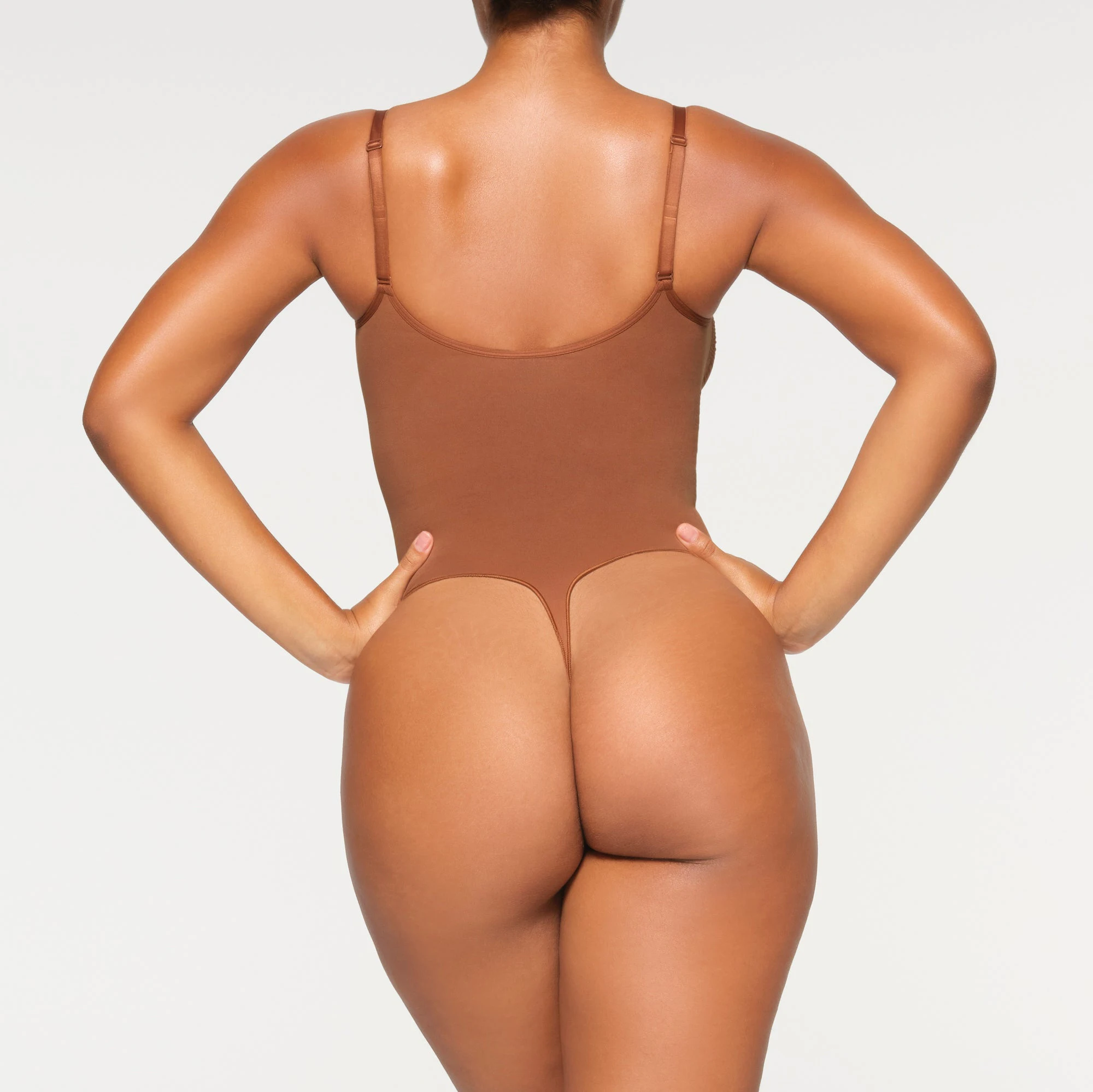 SEAMLESS SCULPT THONG BODYSUIT ON A MODEL BACK VIEW