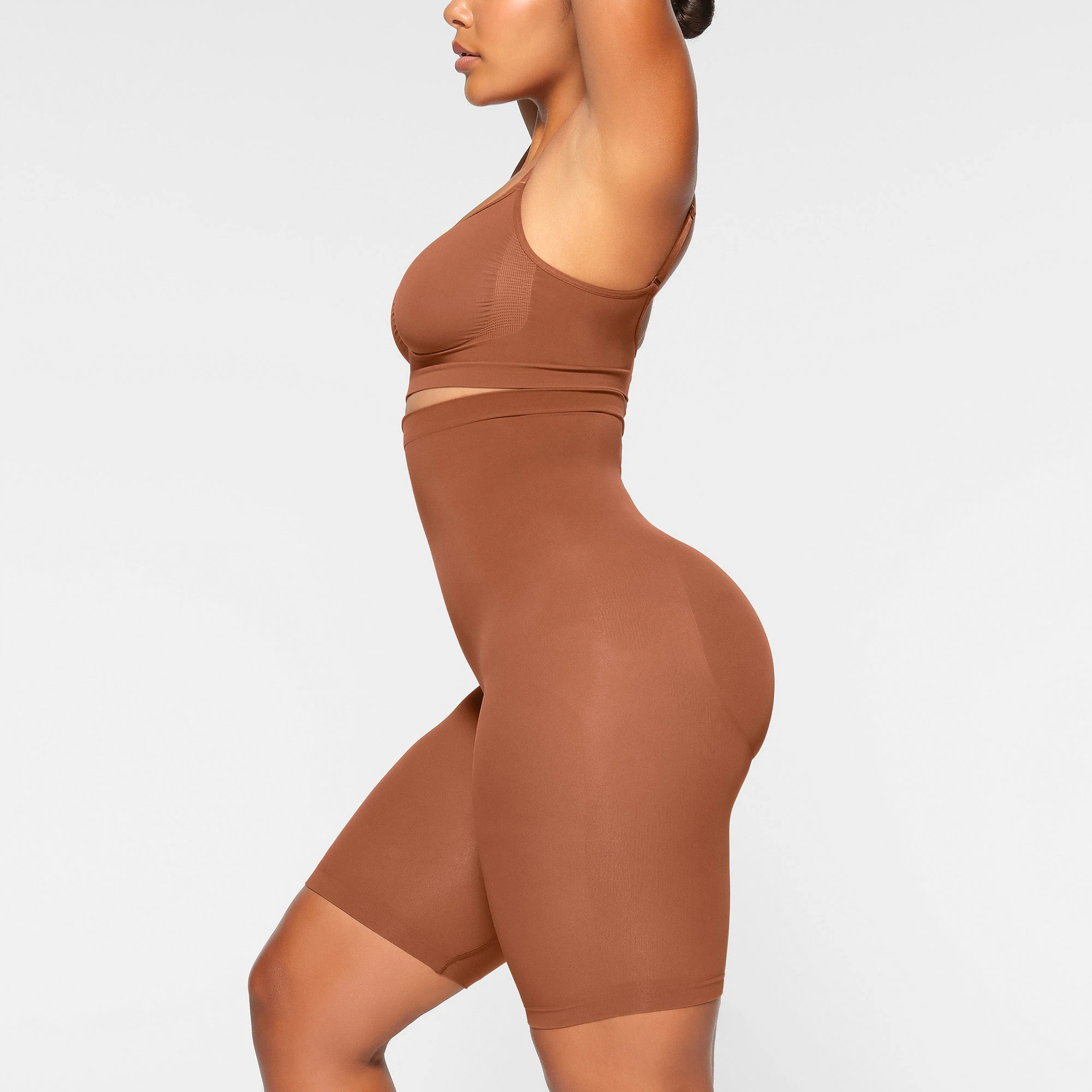 SEAMLESS SCULPT HIGH-WAISTED ABOVE THE KNEE SHORT WORN BY A MODEL IN SIDE VIEW
