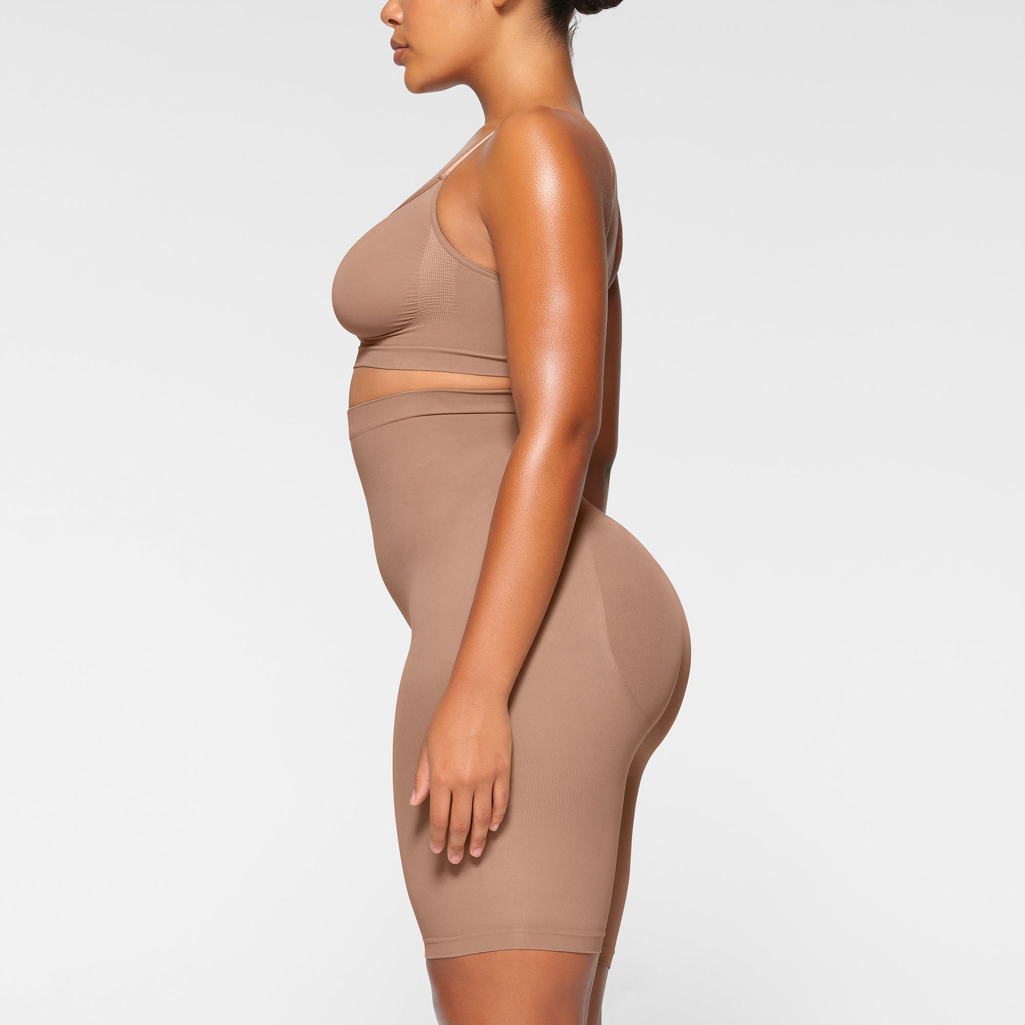 SEAMLESS SCULPT HIGH-WAISTED ABOVE THE KNEE SHORT WORN BY A MODEL IN SIDE VIEW