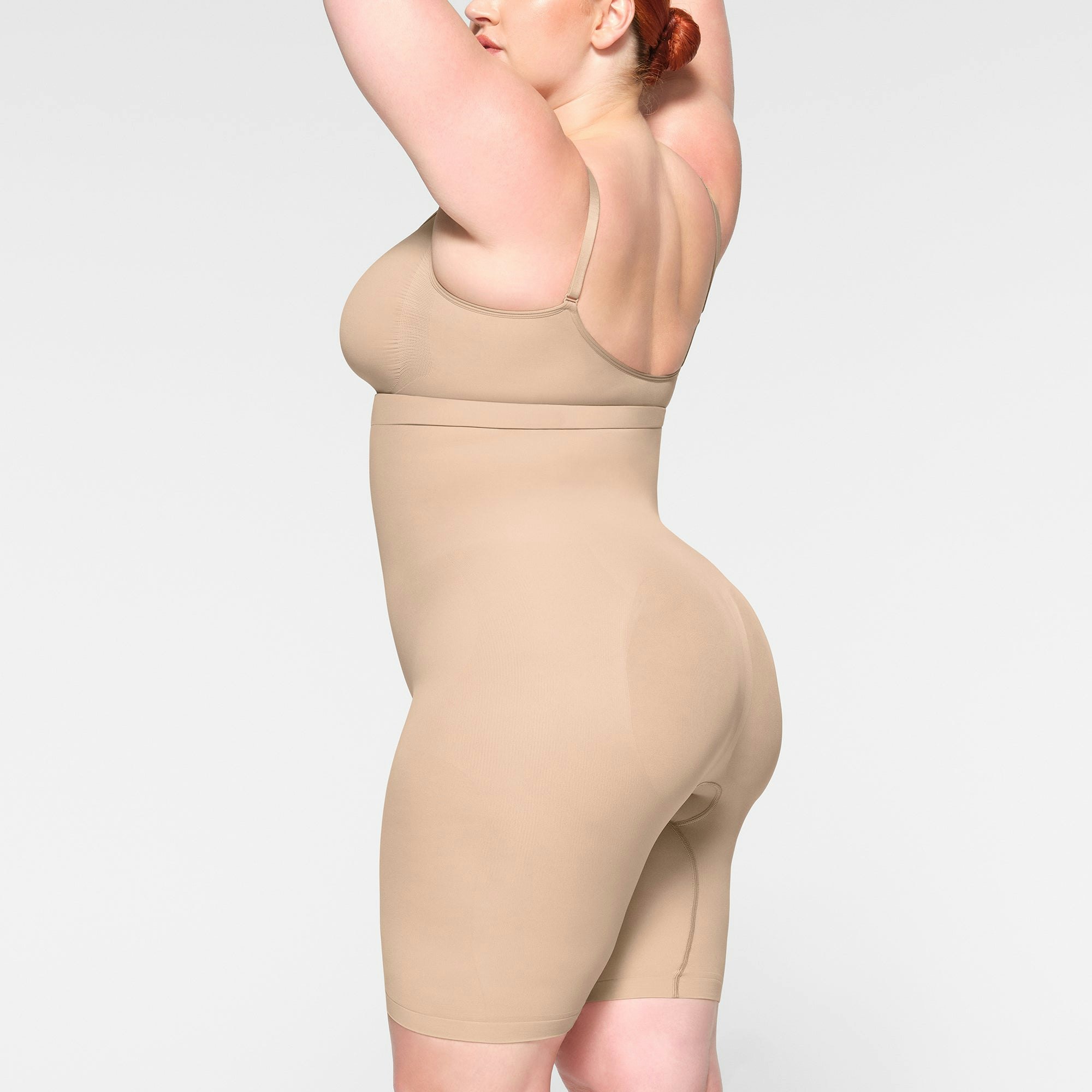 SEAMLESS SCULPT HIGH-WAISTED ABOVE THE KNEE SHORT WORN BY A MODEL IN SIDE VIEW
