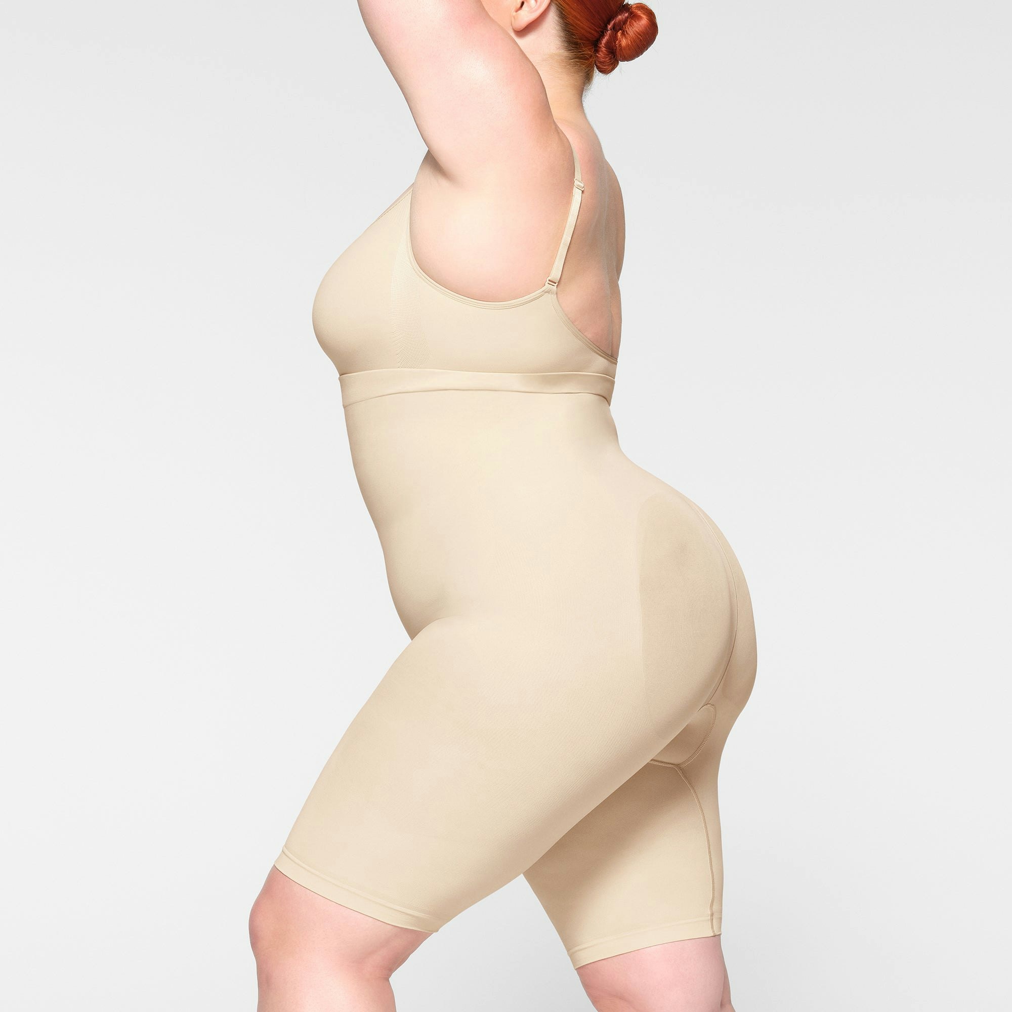 SEAMLESS SCULPT HIGH-WAISTED ABOVE THE KNEE SHORT WORN BY A MODEL IN SIDE VIEW
