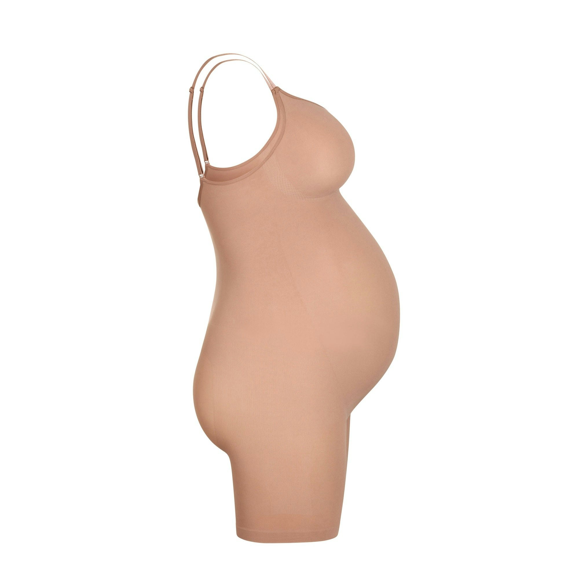 A MODEL STANDS FACING FORWARD WEARING THE MATERNITY SCULPTING BODYSUIT MID THIGH | SIENNA